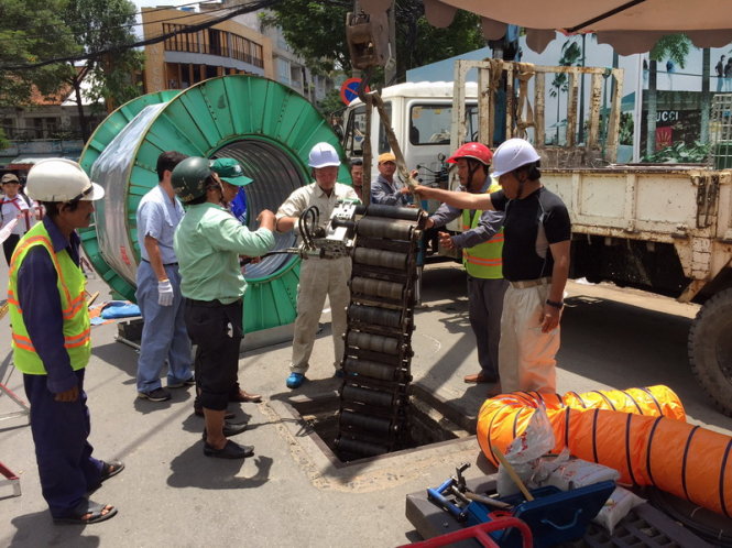 Các kỹ sư Nhật đưa thiết bị quấn lá thép xuống hố ga phục vụ thi công sửa chữa cống thoát nước khu vực vòng xoay Cống Quỳnh - Nguyễn Cư Trinh, Q.1 - Ảnh: Lai Quốc Huy